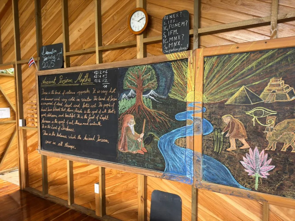 Student writing and drawing about shelters of the world on a chalkboard inside a RISE classroom