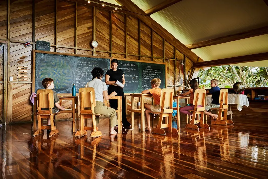 Children running on the grass field in front of the built open-air dome-like classrooms of the RISE Waldorf school