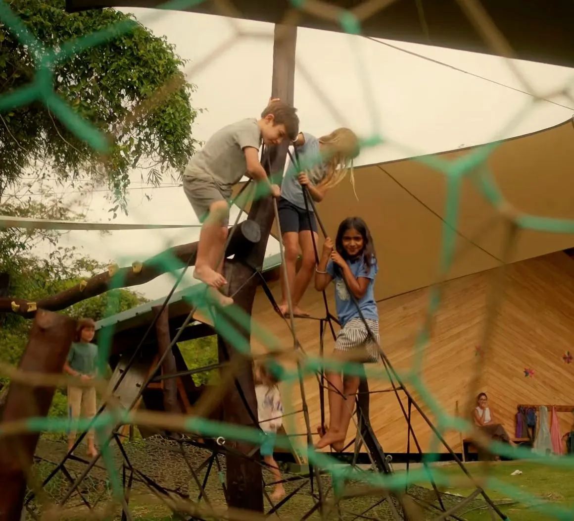 Children climbing and playing on outdoor structures at the RISE School
